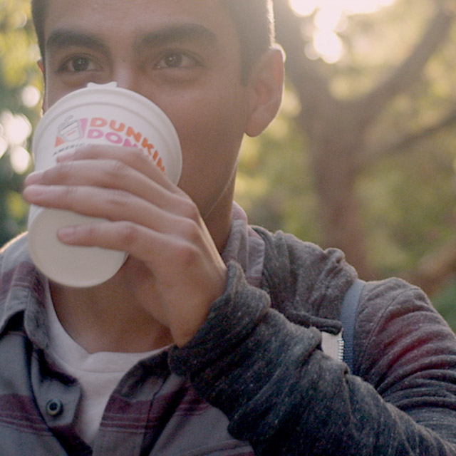A man drinking a Dunkin' Donuts hot beverage.