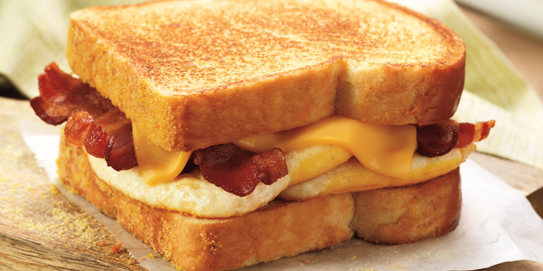 Dunkin’ Donuts Big N’ Toasted® Breakfast sandwich on a wood table.